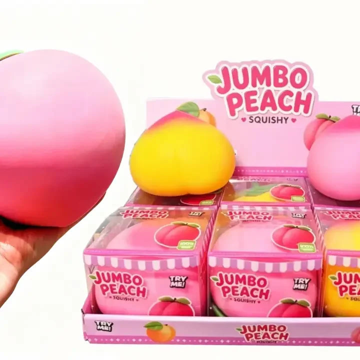 Squishy durazno jumbo rosa en la mano junto al exhibidor de cajas (imagen de referencia de la linea)